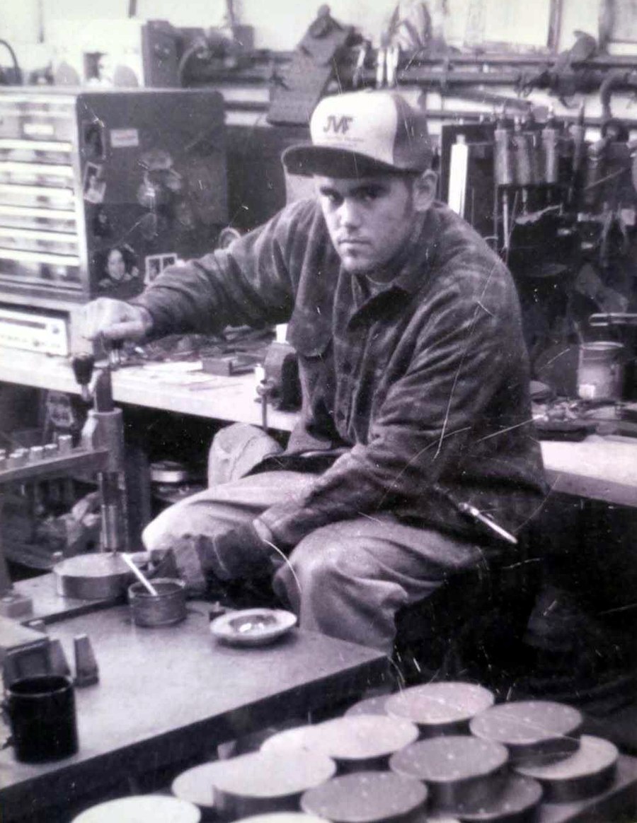 Sean Wilcox at a workbench, rows of finished parts in front of him