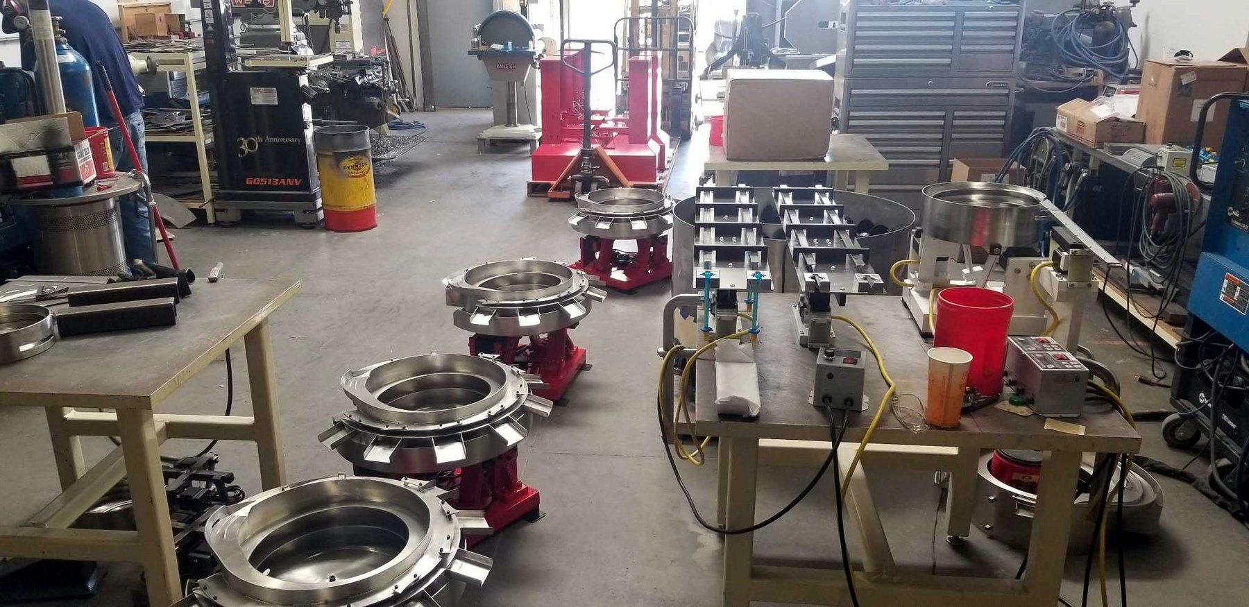 The shop floor with several stainless feeder bowls in build on their drive bases, benches and tooling around them